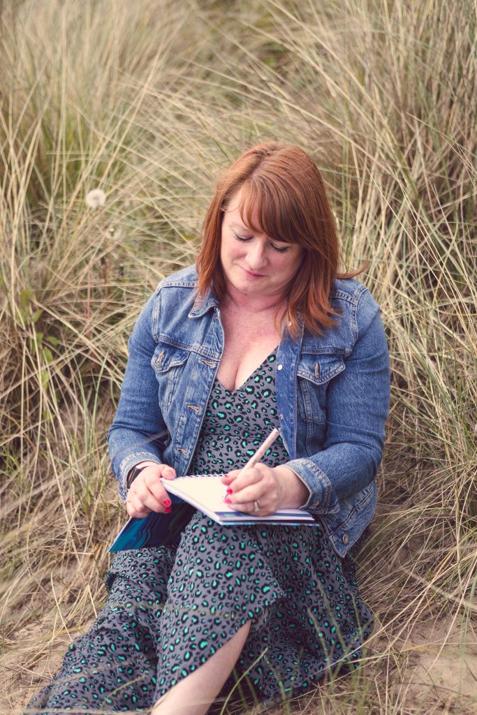 Google updates. Suzy Stanton sitting in long grass writing in a notebook