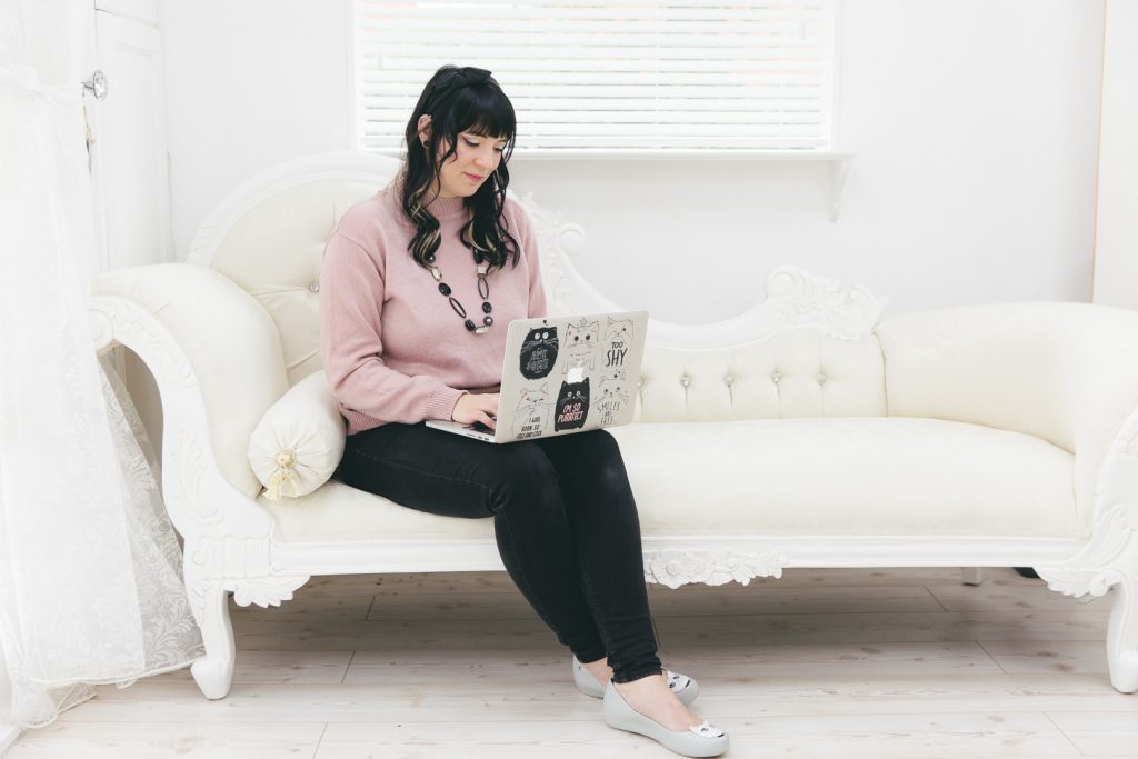 Eloise Adams sitting on a white sofa with her laptop on her knee