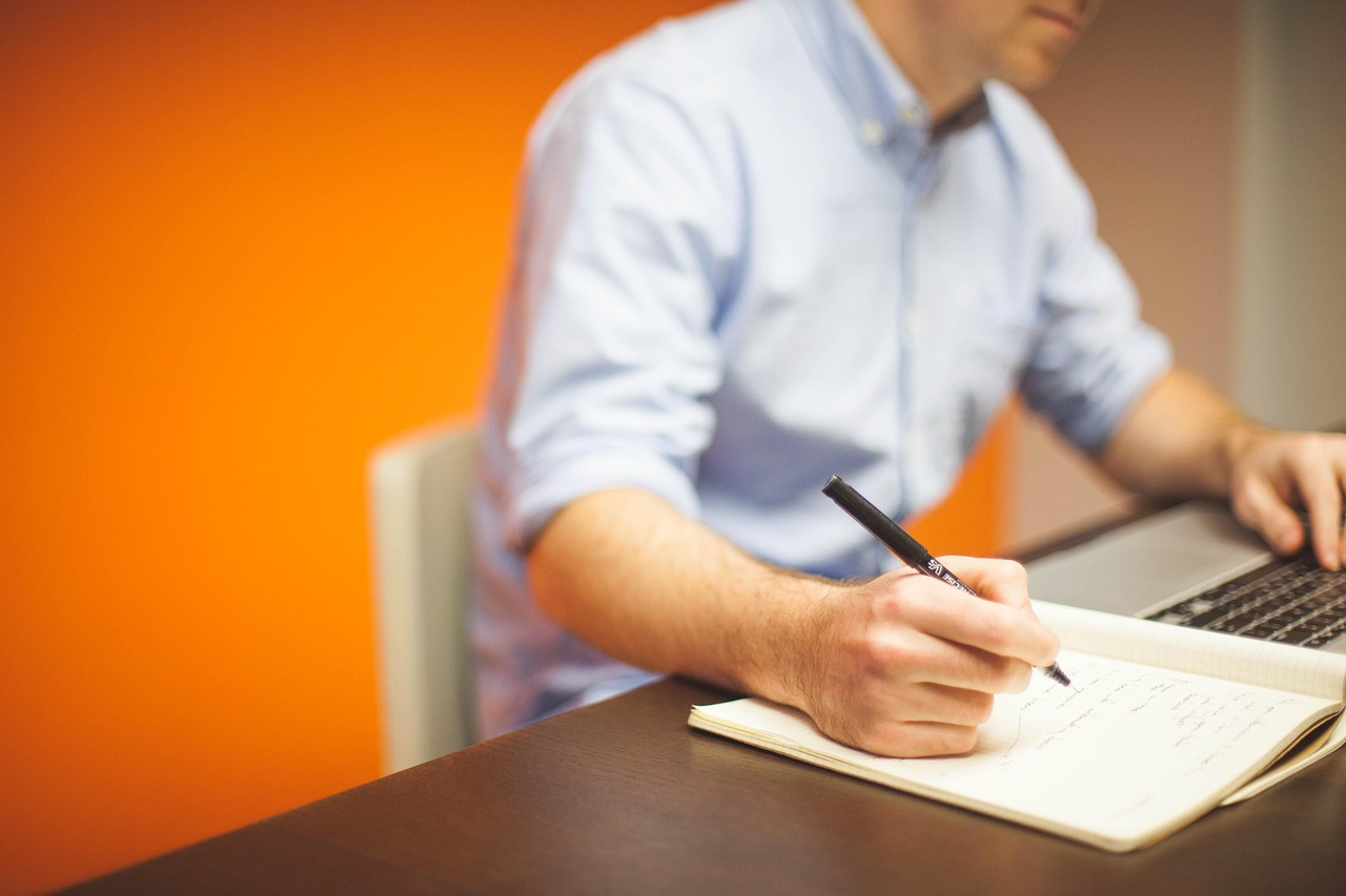 A man sitting at a desk writing a list of reasons why a small business needs a website