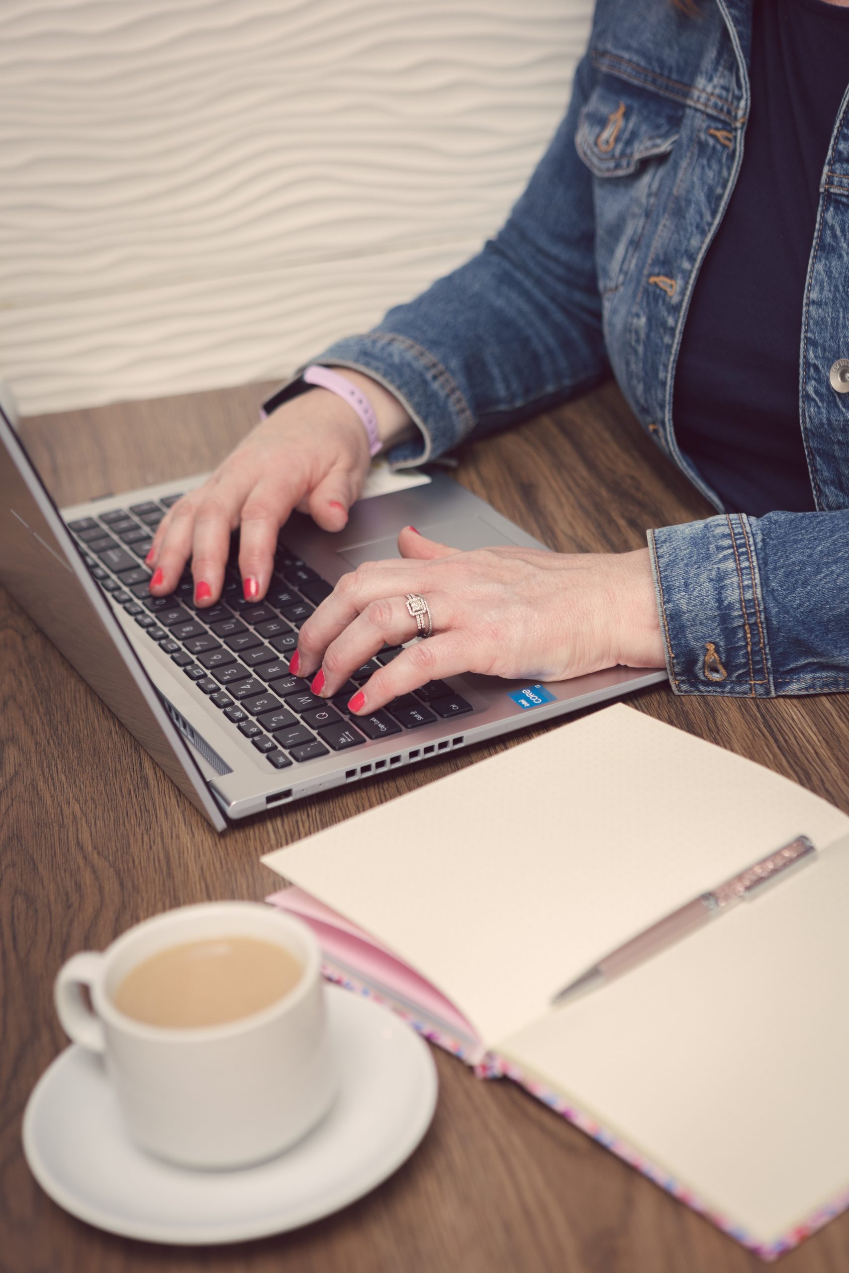 Affordable SEO Services with Suzy's hands typing on a keyboard, next to an open notebook and cup of tea.